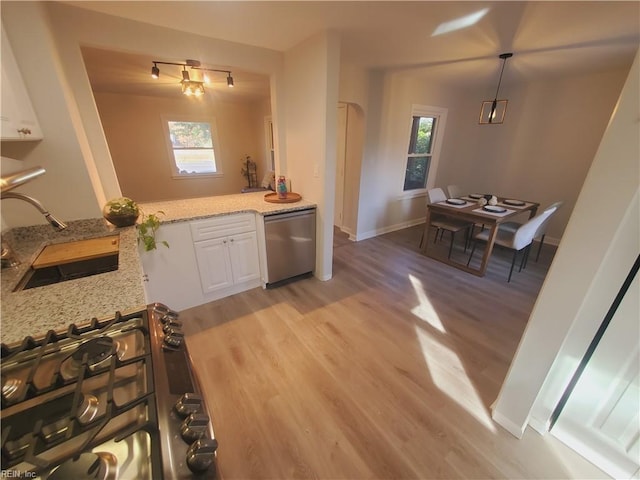 kitchen with light stone counters, stainless steel appliances, sink, white cabinets, and light hardwood / wood-style floors