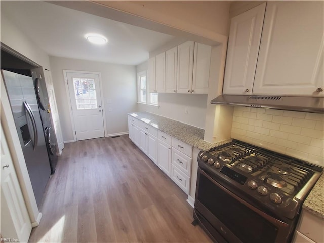 kitchen featuring white cabinets, black gas range, light hardwood / wood-style floors, and light stone countertops