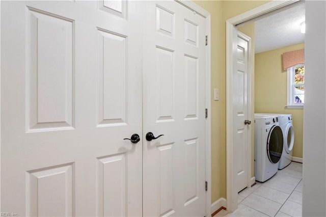 laundry area featuring washer and clothes dryer, light tile patterned flooring, and a textured ceiling