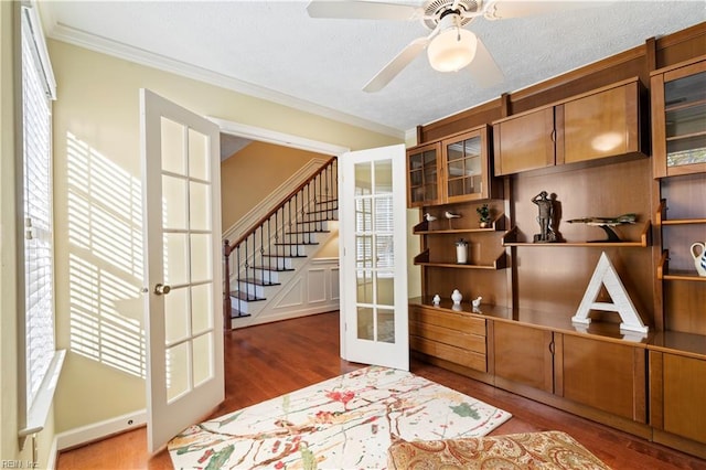 interior space with french doors, wood-type flooring, plenty of natural light, and ornamental molding