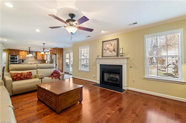 living room with dark hardwood / wood-style floors, ceiling fan, and crown molding