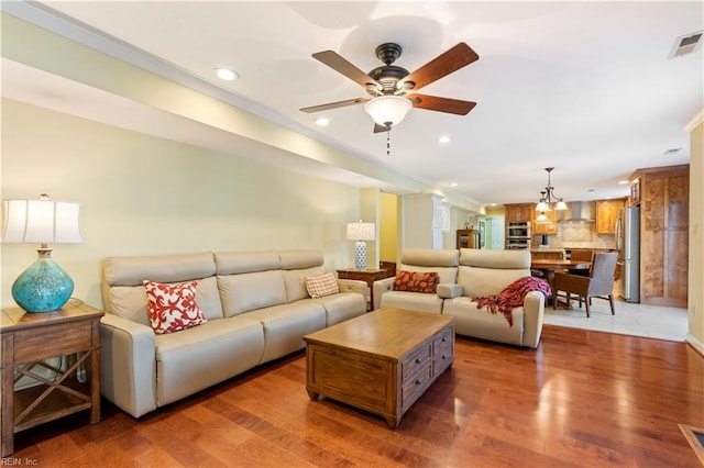 living room with ceiling fan with notable chandelier and dark hardwood / wood-style flooring