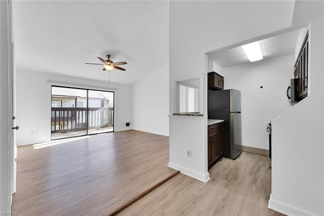 interior space featuring appliances with stainless steel finishes, light wood-type flooring, a textured ceiling, dark brown cabinetry, and ceiling fan