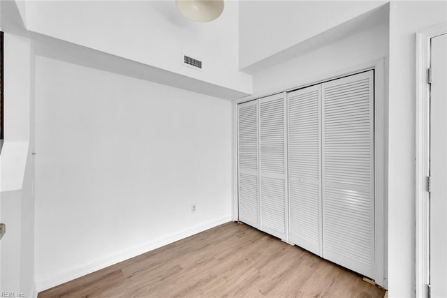 unfurnished bedroom with light wood-type flooring and a closet