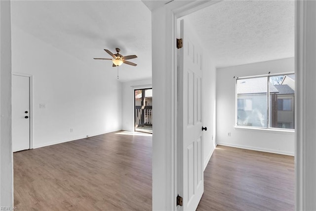 interior space with hardwood / wood-style floors, ceiling fan, lofted ceiling, and a textured ceiling