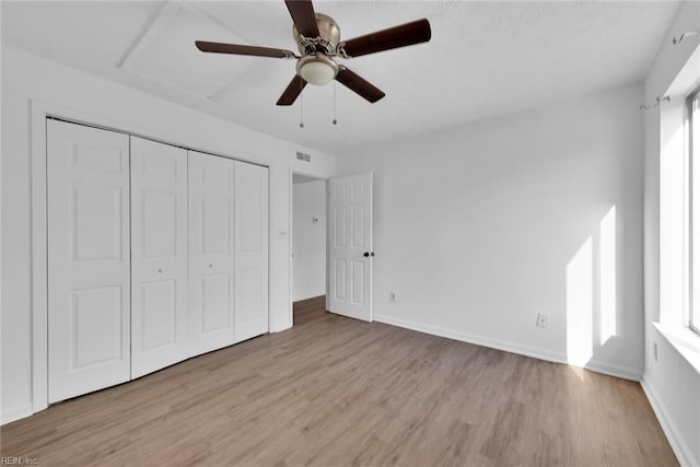 unfurnished bedroom with ceiling fan, light wood-type flooring, and a closet