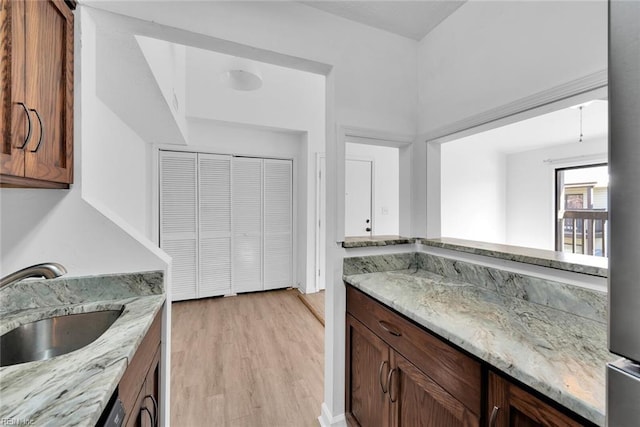 kitchen with light stone counters, light wood-type flooring, and sink