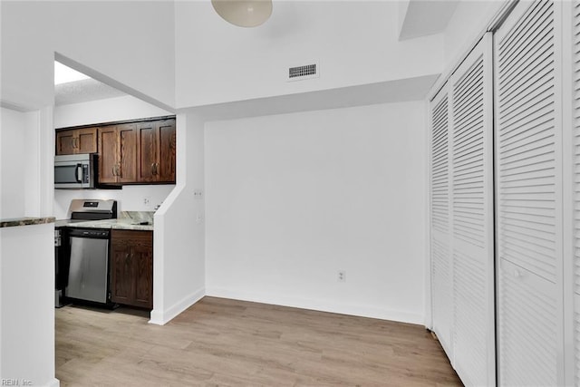 kitchen with light hardwood / wood-style flooring, dark brown cabinets, and appliances with stainless steel finishes