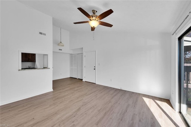 unfurnished living room featuring ceiling fan, light hardwood / wood-style flooring, and high vaulted ceiling