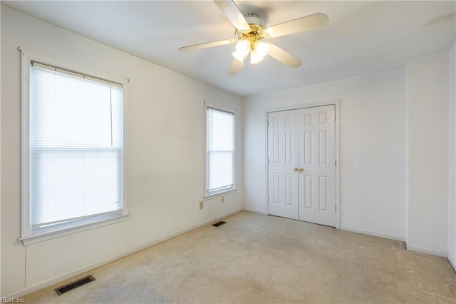 unfurnished bedroom featuring light carpet, a closet, and ceiling fan