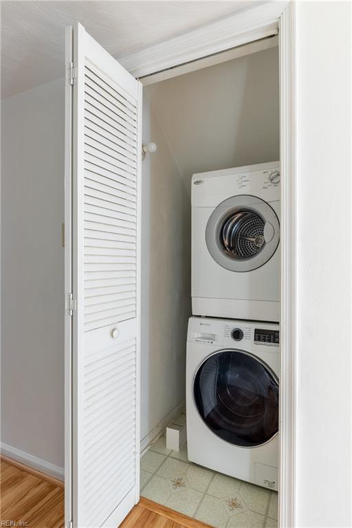 laundry room featuring stacked washer and dryer and light hardwood / wood-style floors