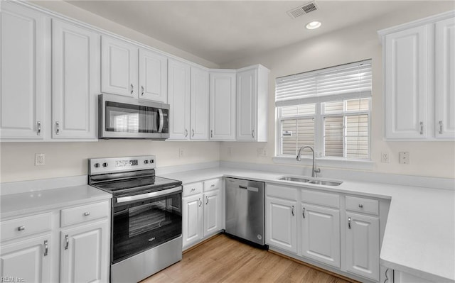 kitchen featuring stainless steel appliances, white cabinetry, light hardwood / wood-style floors, and sink