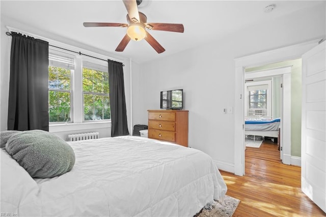 bedroom with radiator heating unit, light wood-type flooring, and ceiling fan