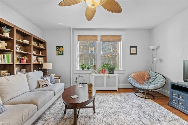 living area featuring ceiling fan, wood-type flooring, and radiator heating unit