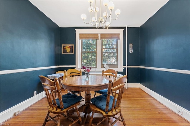 dining space with light hardwood / wood-style floors, an inviting chandelier, and lofted ceiling