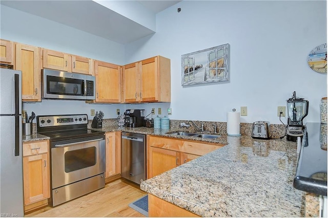 kitchen with sink, stainless steel appliances, light stone counters, light hardwood / wood-style floors, and light brown cabinetry