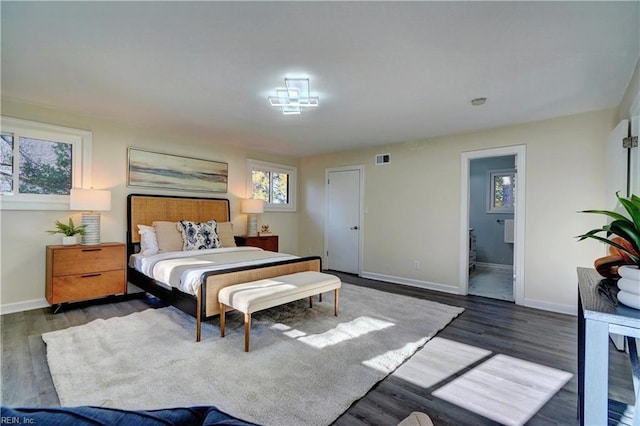 bedroom featuring ensuite bathroom and dark wood-type flooring