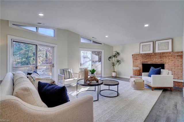 living room featuring a fireplace, plenty of natural light, light hardwood / wood-style floors, and vaulted ceiling