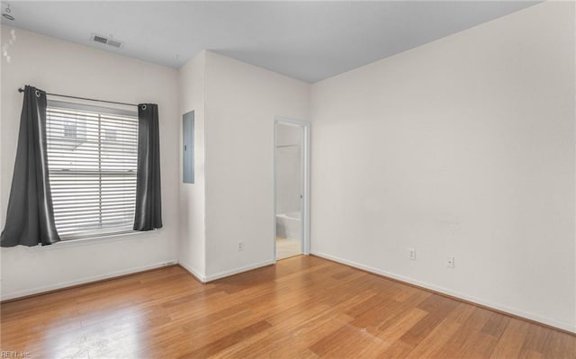 spare room with electric panel and light hardwood / wood-style floors