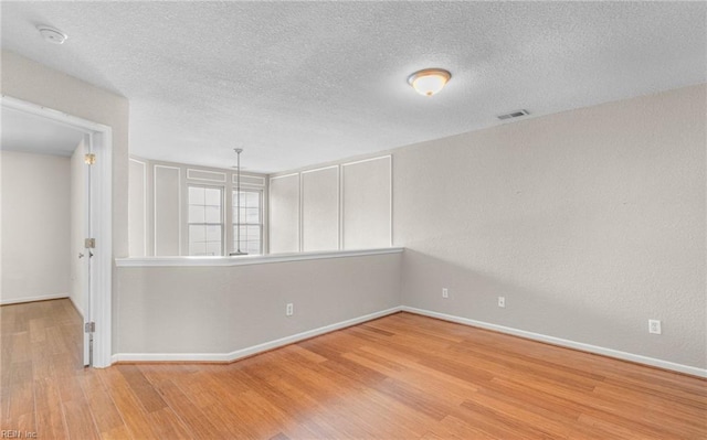 spare room with a textured ceiling and light hardwood / wood-style flooring