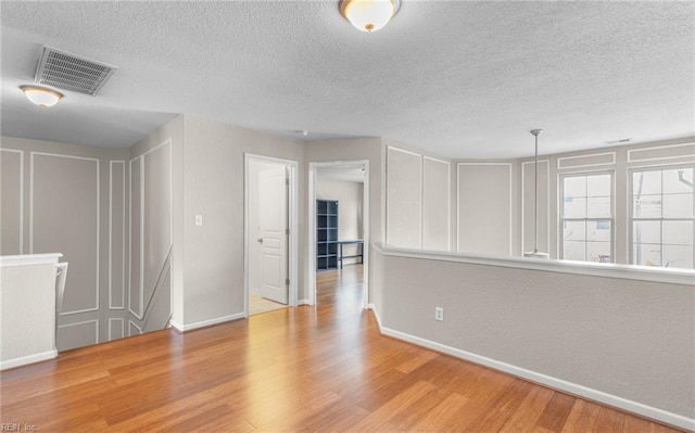 unfurnished room with a textured ceiling and light hardwood / wood-style flooring