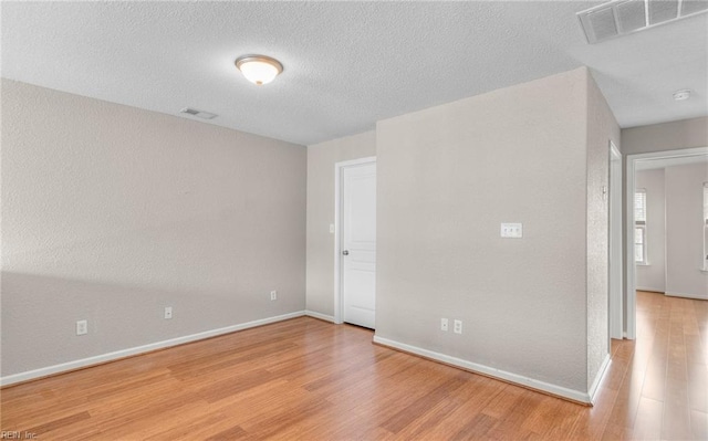 spare room featuring a textured ceiling and light hardwood / wood-style floors