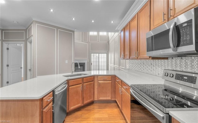 kitchen with backsplash, sink, appliances with stainless steel finishes, light hardwood / wood-style floors, and kitchen peninsula