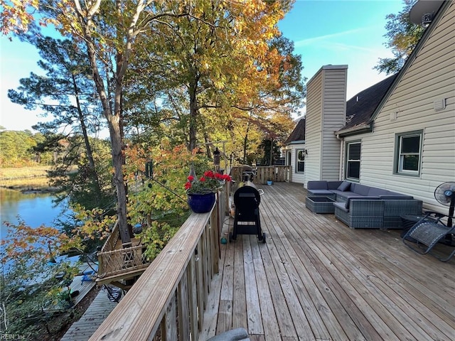 wooden deck featuring area for grilling, an outdoor living space, and a water view