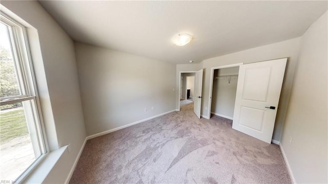 unfurnished bedroom with light carpet and a closet