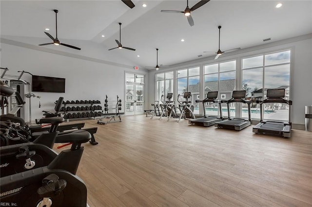 gym featuring a healthy amount of sunlight, ceiling fan, light hardwood / wood-style floors, and vaulted ceiling