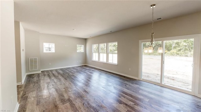 spare room featuring dark hardwood / wood-style floors and an inviting chandelier