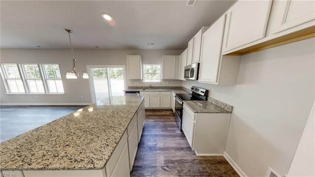 kitchen with pendant lighting, stainless steel appliances, white cabinetry, and a kitchen island