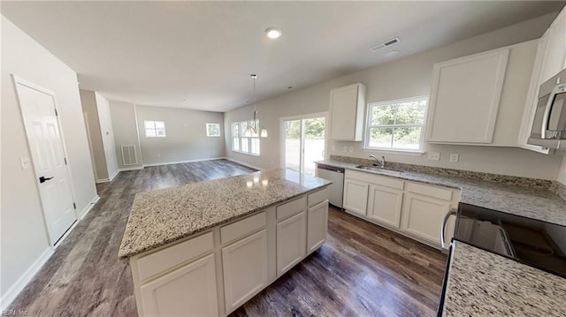 kitchen with white cabinetry, a center island, sink, stainless steel appliances, and dark hardwood / wood-style flooring