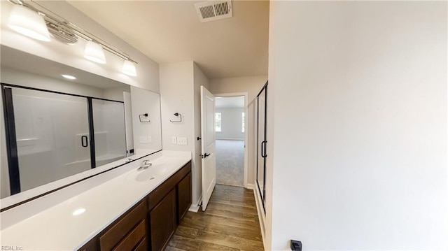 bathroom with hardwood / wood-style floors, vanity, and a shower with shower door