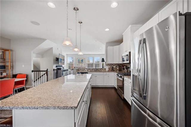 kitchen with pendant lighting, a kitchen island, dark hardwood / wood-style flooring, white cabinetry, and stainless steel appliances