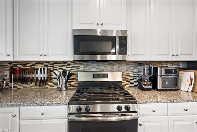 kitchen featuring white cabinets, decorative backsplash, and appliances with stainless steel finishes