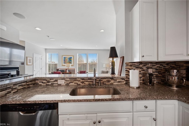 kitchen featuring backsplash, sink, dark stone countertops, dishwasher, and white cabinetry