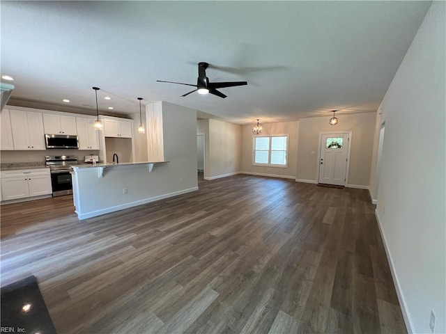 unfurnished living room featuring dark hardwood / wood-style floors and ceiling fan with notable chandelier