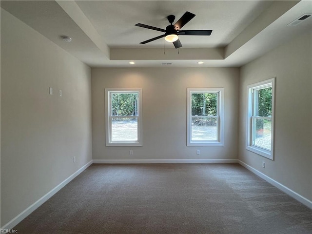 carpeted spare room with ceiling fan and a raised ceiling