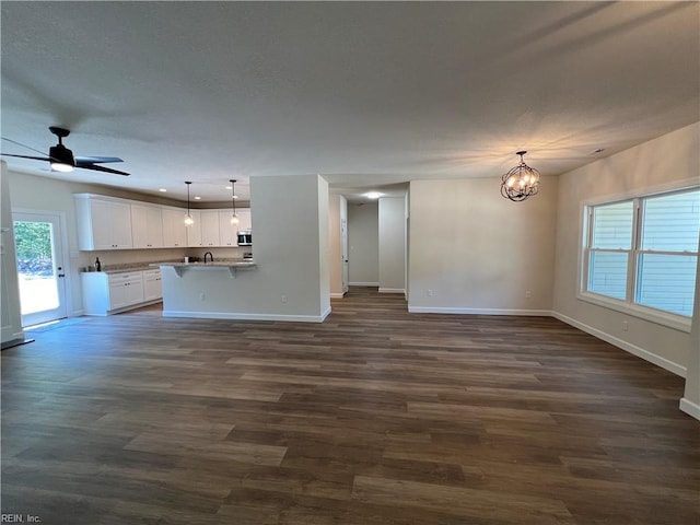 unfurnished living room with ceiling fan with notable chandelier, dark hardwood / wood-style flooring, and sink