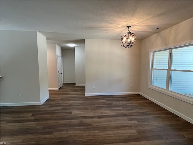 unfurnished room with a textured ceiling, dark hardwood / wood-style floors, and an inviting chandelier