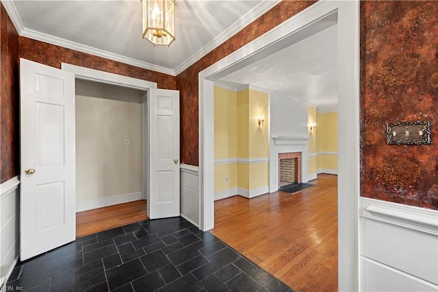 foyer entrance featuring crown molding, dark hardwood / wood-style flooring, and a brick fireplace