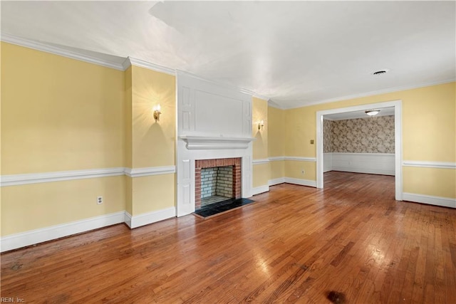 unfurnished living room featuring hardwood / wood-style floors, crown molding, and a brick fireplace