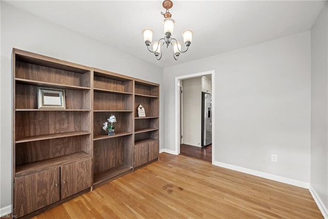 spare room featuring light hardwood / wood-style floors and an inviting chandelier