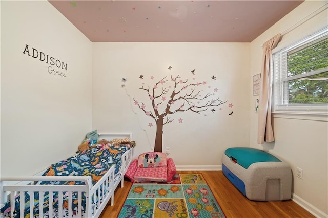 bedroom featuring hardwood / wood-style floors and a crib