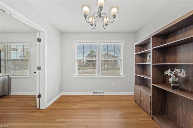 dining room with a wealth of natural light, light hardwood / wood-style floors, and a notable chandelier