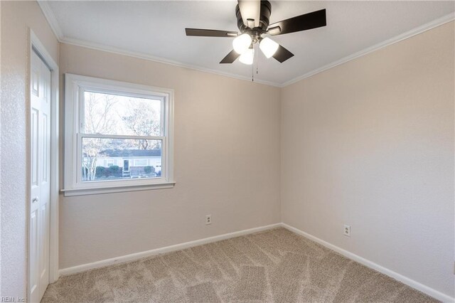 carpeted spare room with ceiling fan and ornamental molding