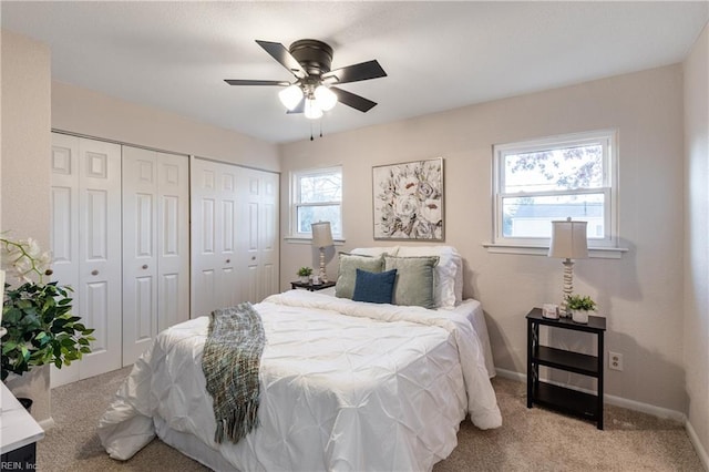 bedroom featuring ceiling fan, light carpet, and multiple closets