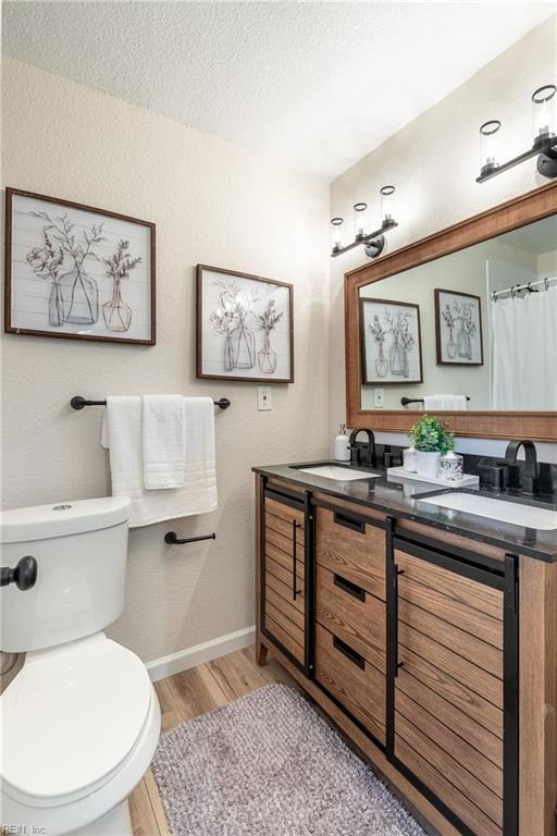 bathroom featuring vanity, wood-type flooring, a textured ceiling, and toilet