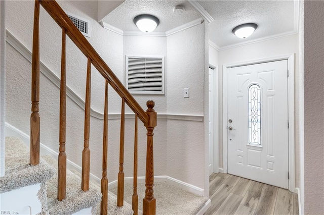 foyer featuring crown molding, light hardwood / wood-style floors, and a textured ceiling